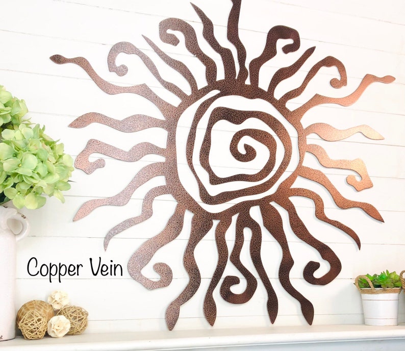 May include: A copper vein metal sunburst wall art piece. The sun design features a textured finish and a swirling centre. The text "Copper Vein" is visible in the image. The sun's rays extend outwards in various shapes.