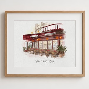 May include: A framed watercolor illustration of a cafe exterior with a red awning, outdoor seating, and potted plants. The text reads Our First Date and SEPTEMBER 20, 2024. The artwork is enclosed in a light wood frame with a white mat border.