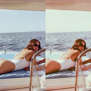 May include: A woman wearing a white swimsuit and sunglasses is lying on a boat deck. The sea is in the background.