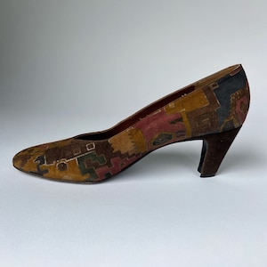 May include: A pair of brown suede heeled shoes with a geometric pattern in shades of brown, red, green, and blue.