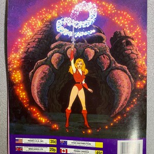 Może przedstawiać: Vintage naklejka Panini z kresk&oacute;wkową ilustracją wojowniczki w czerwonym stroju, trzymającej miecz w g&oacute;rze. Stoi przed dużą konstrukcją z efektem świecącej energii. Naklejka ma tekst na dole.