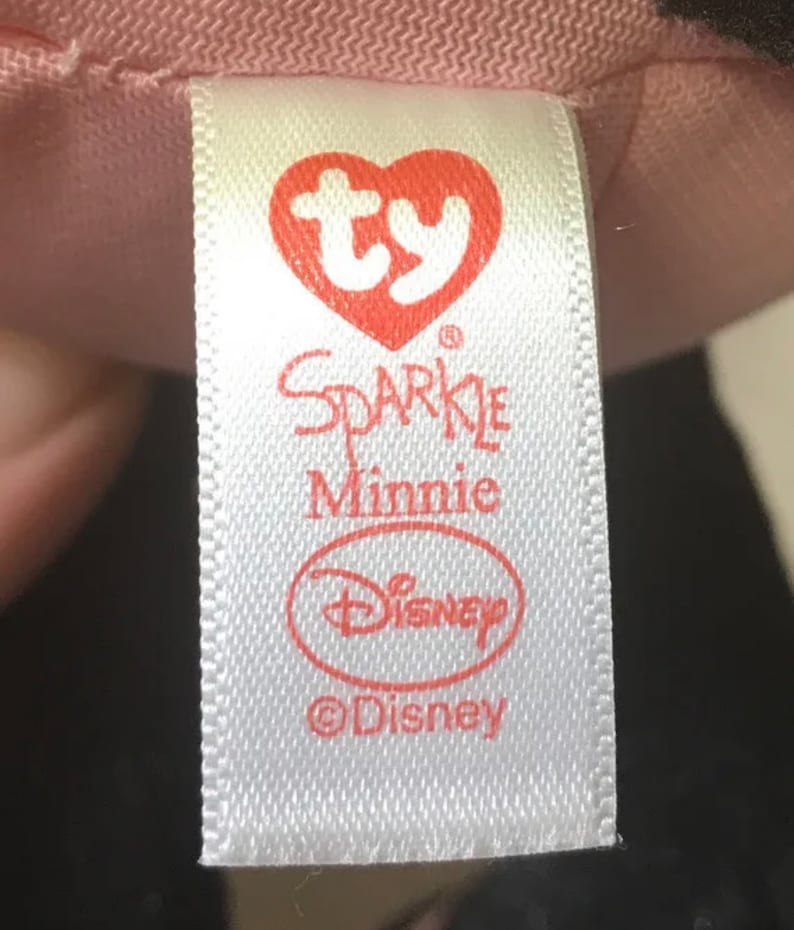 May include: White tag with red text and a red heart with the letters "ty" inside. The tag says "Sparkle Minnie" and has the Disney logo and copyright symbol.