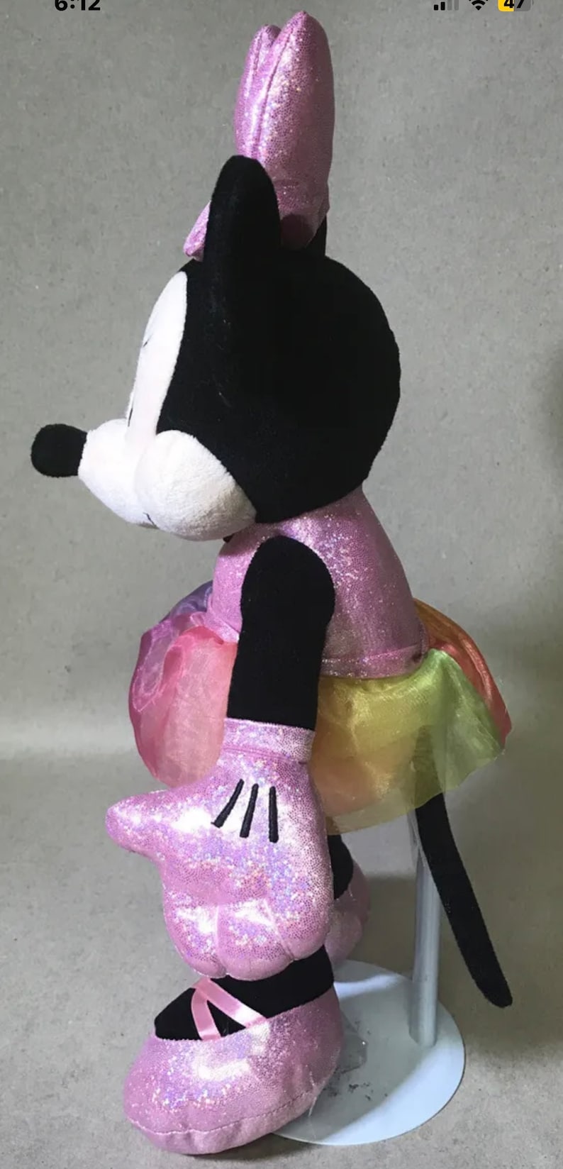 May include: A pink and black plush Minnie Mouse doll wearing a sparkly pink dress with a rainbow tulle skirt and pink shoes.