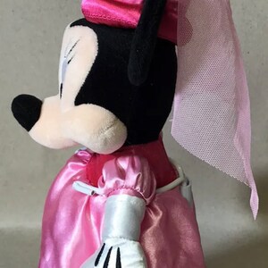 K&ouml;nnte beinhalten: Rosa Pl&uuml;sch-Minnie Maus, verkleidet als Prinzessin mit einem rosa Satin-Kleid, wei&szlig;en Handschuhen und einer rosa Krone mit einem T&uuml;ll-Schleier.