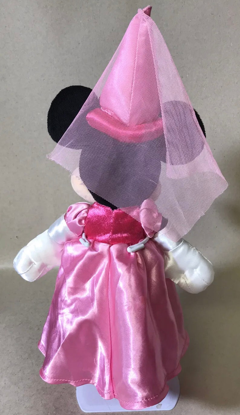 K&ouml;nnte beinhalten: Eine rosafarbene und wei&szlig;e Pl&uuml;sch-Minnie-Maus-Puppe, die ein rosafarbenes Kleid und einen rosafarbenen T&uuml;llschleier tr&auml;gt.