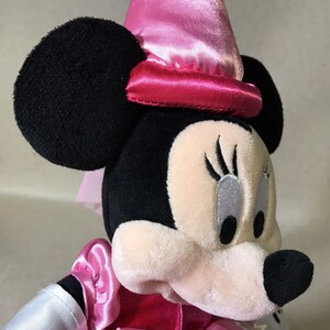 K&ouml;nnte beinhalten: Ein rosa und schwarzes Pl&uuml;schtier einer Maus, die einen rosa Hut mit einer rosa Satinschleife tr&auml;gt. Die Maus hat schwarze Augen und eine wei&szlig;e Nase.