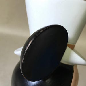 May include: A black and white figurine of a cartoon character wearing a top hat. The figurine has large black ears, a white hat, and a black body. The character's face is not visible in the image.