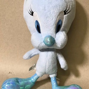 May include: A light blue plush Tweety Bird toy with iridescent blue feet. The toy has embroidered eyes and a black beak.