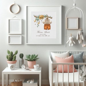 Op de afbeelding: Een ingelijste aquarelprint met een babyoutfit, hoed en bloemaccenten. De print bevat de naam "Thomas Smith" en geboortegegevens. De kinderkamerdecoratie omvat ook een witte wieg, knuffels en potplanten.