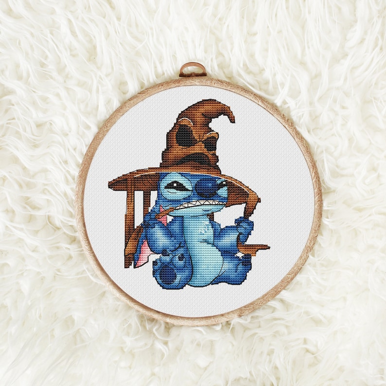 K&ouml;nnte beinhalten: Eine blaue Stitch-Figur, die einen braunen spitzen Hut tr&auml;gt, sitzt auf einem Stuhl mit einem braunen Tisch. Die Figur h&auml;lt einen Zauberstab in der rechten Hand.