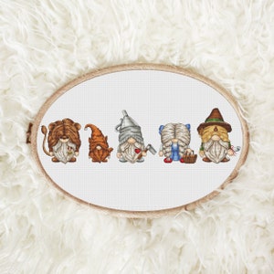 May include: A set of six embroidered gnomes, each representing a character from the Wizard of Oz. The gnomes are lined up in a row, from left to right: Cowardly Lion, Tin Man, Scarecrow, Dorothy, Wicked Witch of the West, and the Wizard.