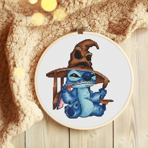K&ouml;nnte beinhalten: Eine blaue Stitch-Figur, die einen braunen Sortierhut aus der Harry-Potter-Reihe tr&auml;gt. Stitch h&auml;lt in der einen Hand einen Zauberstab und in der anderen ein Buch. Die Figur sitzt auf einem Stuhl vor einem wei&szlig;en Hintergrund.