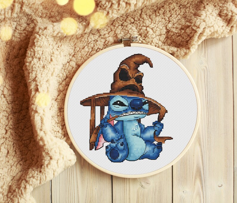 K&ouml;nnte beinhalten: Eine blaue Stitch-Figur, die einen braunen Sortierhut aus der Harry-Potter-Reihe tr&auml;gt. Stitch h&auml;lt in der einen Hand einen Zauberstab und in der anderen ein Buch. Die Figur sitzt auf einem Stuhl vor einem wei&szlig;en Hintergrund.