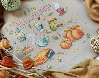 May include: Cross stitch pattern featuring a fall theme with the text "HELLO SEPTEMBER". The pattern includes a pumpkin, a teapot, a lantern, a cup of coffee, a slice of pie, a boot, and a cornucopia.