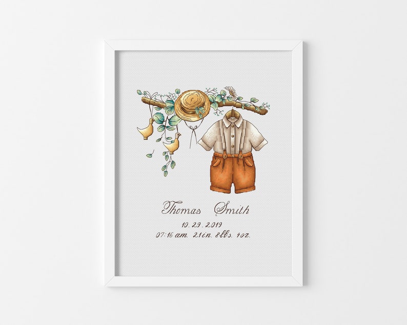 Op de afbeelding: Een ingelijste aquarelprint met een babyoutfit, een strohoed en decoratieve elementen. De outfit bestaat uit een shirt met korte mouwen en een korte broek met bretels. De print bevat de naam "Thomas Smith", datum, tijd, lengte en gewicht.