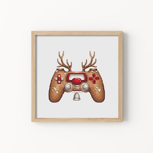 Puede incluir: Un mando de videojuego pixelado marrón y blanco con botones rojos y cuernos de reno, enmarcado en un marco de madera claro.