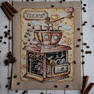 Op de afbeelding: Een kruissteekborduursel van een steampunk-koffiemaler met ingewikkelde tandwielen en pijpen. De maler is van metaal en heeft een houten basis. De tekst "Steampunk Coffee" staat op een bord boven de maler.