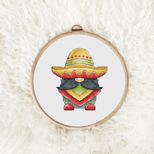 May include: A colorful gnome wearing a traditional Mexican sombrero with red, yellow, and green accents. The gnome has a black beard and is wearing a red and green patterned shirt.