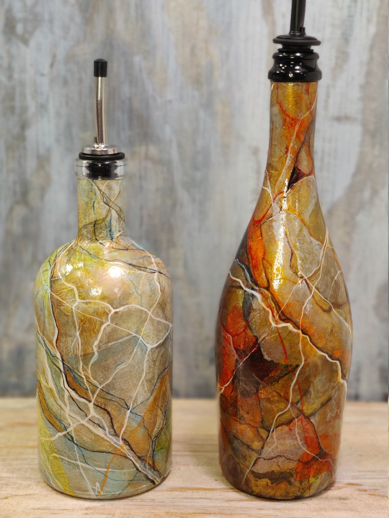 Pu&ograve; includere: Due bottiglie di vetro con vernice marmorizzata decorativa in tonalit&agrave; di marrone, oro e bianco. Le bottiglie hanno un beccuccio e un tappo.