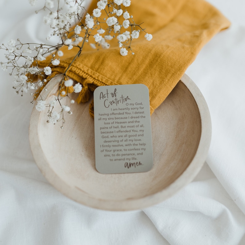 May include: A gray card with the text "Act of Contrition" printed in brown. The card includes a prayer of contrition, ending with the word "amen".