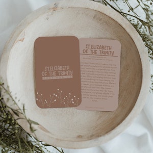 May include: A brown card with a floral design and the text "St. Elizabeth of the Trinity Pray for Us". The back of the card has a prayer to St. Elizabeth of the Trinity.