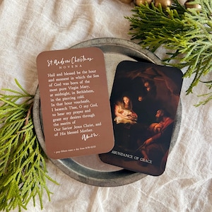 May include: Two Christmas prayer cards. One card is brown with the text "St. Andrew Christmas Novena" and a prayer. The other card has a painting of the Nativity scene and the words "Abundance of Grace".