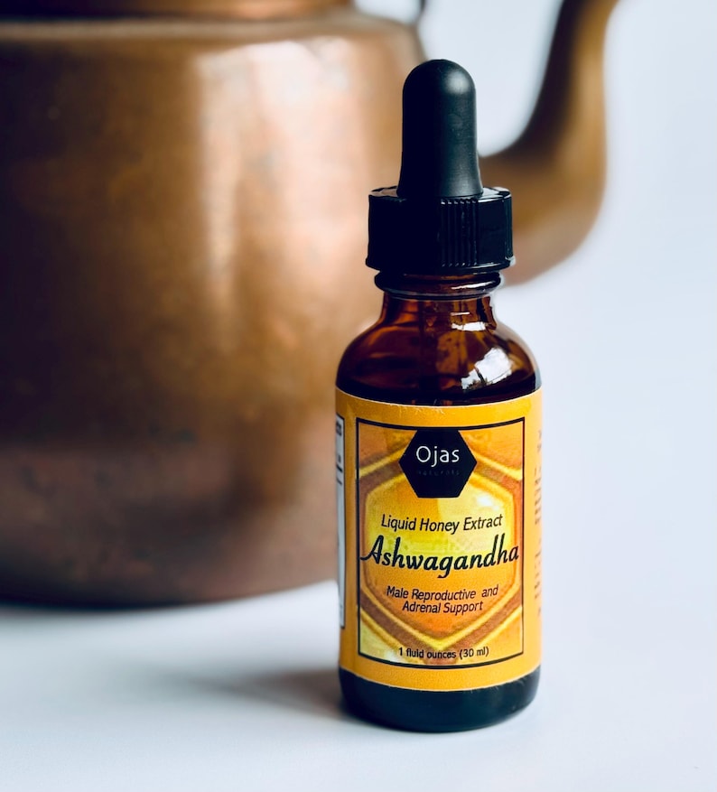 May include: A brown glass bottle with a black dropper top and a yellow label that reads "Ojas Liquid Honey Extract Ashwagandha Male Reproductive and Adrenal Support 1 fluid ounces (30 ml)"