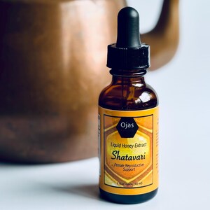 K&ouml;nnte beinhalten: Eine braune Glasflasche mit Tropfer und einem gelben Etikett. Das Etikett lautet "Ojas Fl&uuml;ssiger Honig-Extrakt Shatavari Unterst&uuml;tzung der weiblichen Fortpflanzung 1 Fl&uuml;ssigunze (30 ml)"