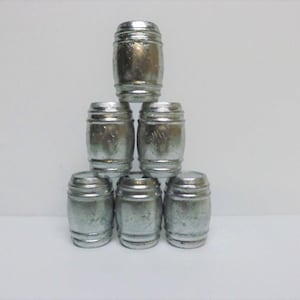 May include: Six silver metal barrels stacked in a pyramid shape. The barrels are small and have a slightly textured surface.