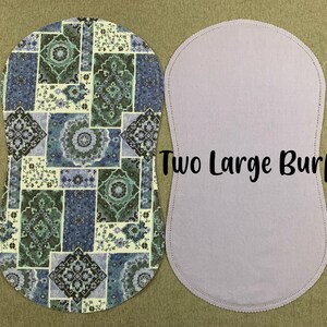 May include: Two large, white burp cloths. One cloth has a patterned design with blue, green, and white colors. The other cloth is plain white.