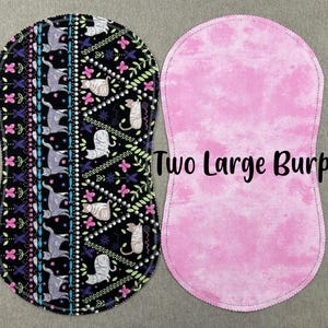 May include: Two large burp cloths, one with a pink and white tie-dye pattern and the other with a black background and a colorful pattern of cats and flowers.