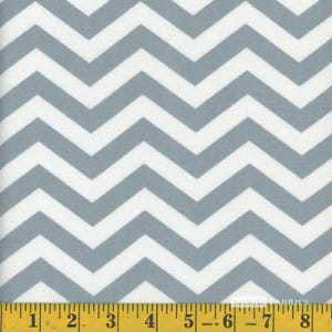 May include: Close-up of a fabric with a repeating chevron pattern in gray and white. The fabric is measured with a yellow measuring tape at the bottom, showing inches. The pattern is a classic design, suitable for various crafting projects.