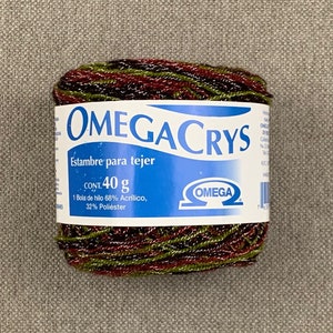 May include: A ball of Omega Crys yarn, featuring a blend of red, green, and black threads. The label reads "Estambre para tejer" and indicates a 40 g weight. The yarn is composed of 68% acrylic and 32% polyester.