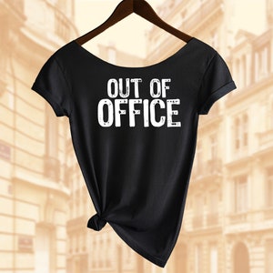 以下が含まれることがあります： 黒地に白の「OUT OF OFFICE」の文字がプリントされたTシャツ。裾が結ばれている。
