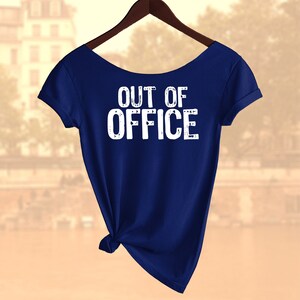 以下が含まれることがあります： 前面に白い文字で「OUT OF OFFICE」とプリントされたネイビーブルーのTシャツです。