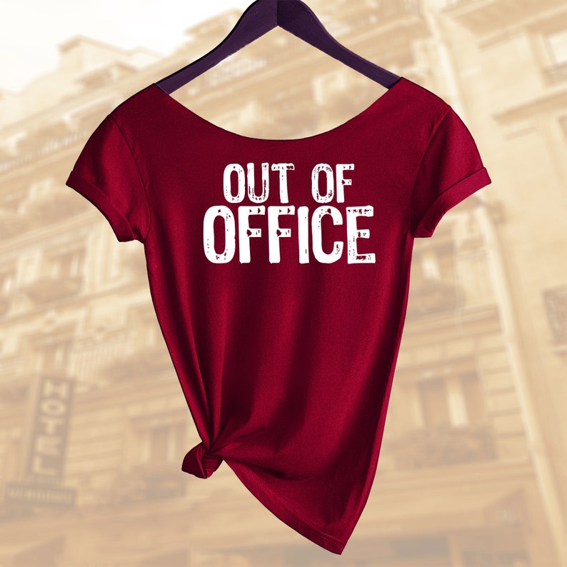 以下が含まれることがあります： 前面に白い文字で「OUT OF OFFICE」とプリントされた、マルーンのTシャツです。