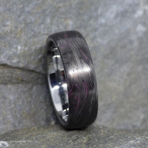 以下が含まれることがあります： 黒と紫のカーボンファイバー製の結婚指輪で、磨かれた仕上げになっています。