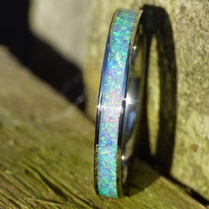 Può includere: Un anello d'argento con una fascia sottile e un'incisione di opale blu e verde.