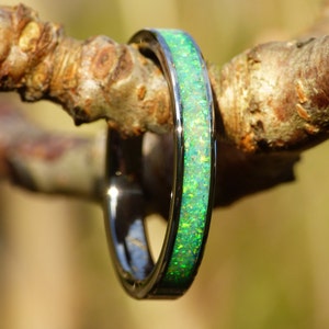 Könnte beinhalten: Ein dünner Silberring mit einem grünen Opal-Inlay. Der Ring befindet sich auf einem Ast.