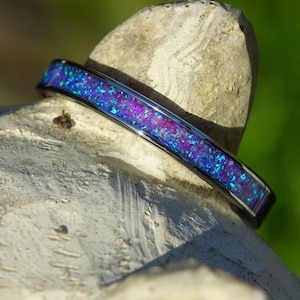 May include: A thin silver band with a blue and purple opal inlay. The band is shown on a textured surface.
