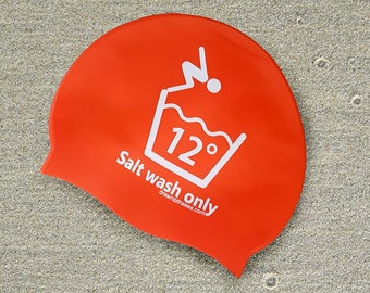 May include: A bright red swim cap with a white graphic of a bucket with a wave and the number 12 degrees. The text "Salt wash only" is printed below the graphic.