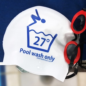 May include: White swim cap with a blue washing instruction icon that says "Pool wash only" and "27&deg;" with a website address. Red swimming goggles with a black strap.
