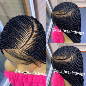 May include: A black braided wig with a lace front and a parting in the middle. The wig is styled in a cornrow pattern with a small design at the top. The wig is shown on a mannequin head with a pink background. The text "@ella_braidedwigs" is visible in the image.