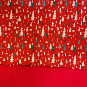 May include: Red fabric with a repeating pattern of white Christmas trees and green gift boxes.