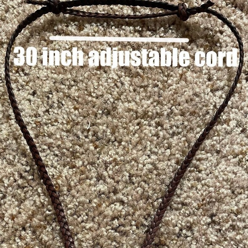 May include: A brown leather cord necklace, 30 inches long, with an adjustable clasp. The cord is braided and has a simple design.