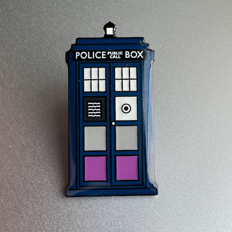 Pode incluir: Um &iacute;man azul em forma de TARDIS com as palavras "POLICE PUBLIC BOX" em branco. O &iacute;man apresenta um topo preto, janelas brancas e pain&eacute;is roxos e cinzentos. O design &eacute; uma r&eacute;plica da ic&oacute;nica cabine telef&oacute;nica brit&acirc;nica.