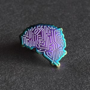 Op de afbeelding: Een regenboogkleurige, iriserende emaille pin in de vorm van een brein met een printplaatontwerp.