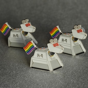 May include: Three white robot dog pins with rainbow flags. Each pin has the text "H-9" on the side.