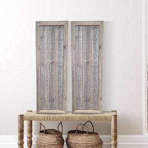 May include: Two framed wood plank wall art prints with a rustic gray and white finish. The prints are displayed on a woven wicker bench with two woven baskets.