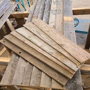 K&ouml;nnte beinhalten: Ein Stapel aus wiederverwendeten Holzbrettern in verschiedenen Braunt&ouml;nen und Graut&ouml;nen. Die Bretter sind versetzt gestapelt und in zwei L&auml;ngen erh&auml;ltlich: 61 cm und 122 cm.